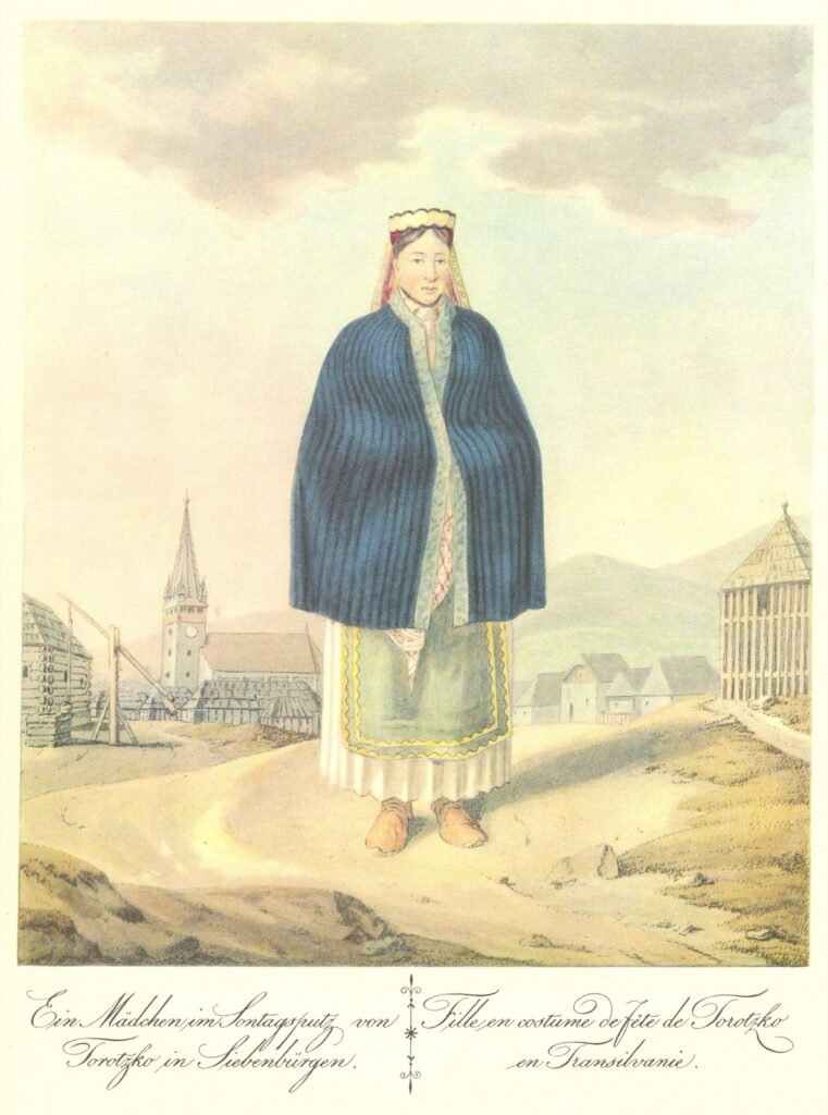 Színezett metszet 1821-ből: torockói leány kék köpenyben és fehér főkötőben, mögötte a templomtorony és a fából épült falu